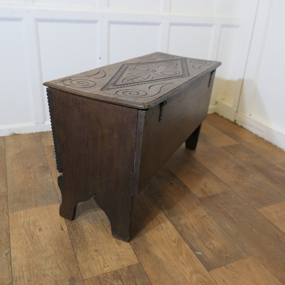 A dark oak plank coffer featuring a geometric carved pattern on the top lid, slab ends, and a central keyhole. View VI