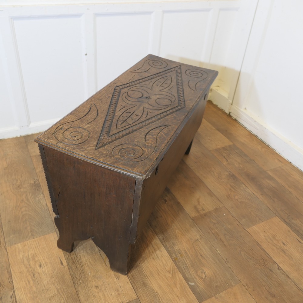 A dark oak plank coffer featuring a geometric carved pattern on the top lid, slab ends, and a central keyhole. View VII