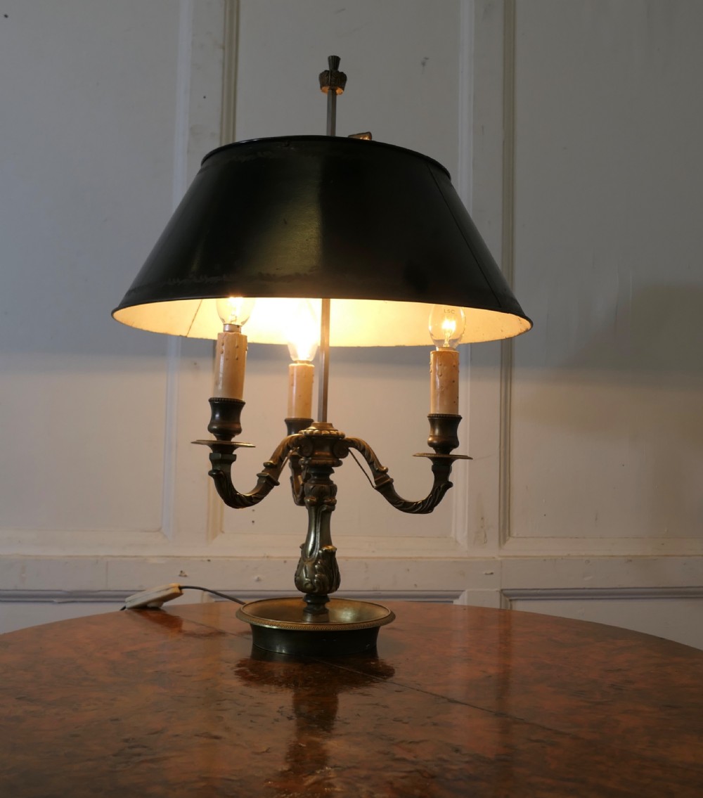 A French triple-light bouillotte lamp featuring a dark green painted toleware shade, three brass candle arms, and a dished brass tray base. View V