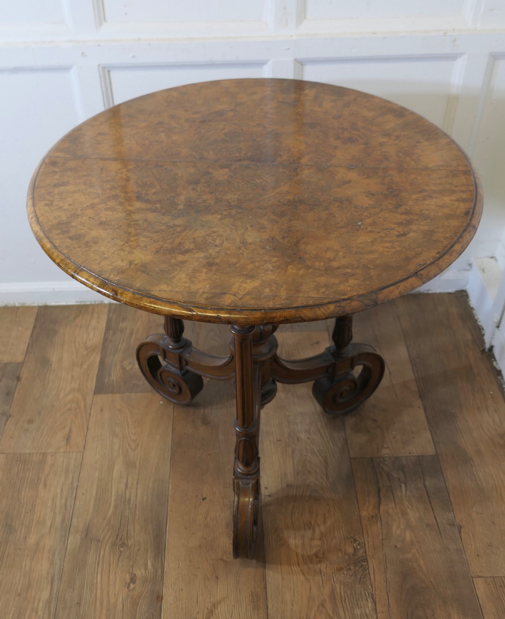 A nineteenth-century burr walnut wine table featuring a circular top supported by turned pillars and carved scroll feet. View III