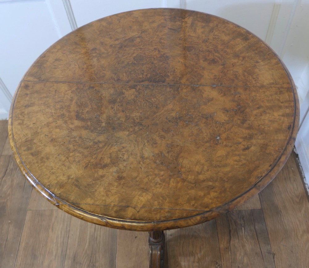 A nineteenth-century burr walnut wine table featuring a circular top supported by turned pillars and carved scroll feet. View VI