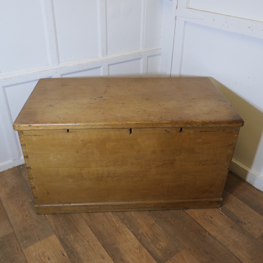A large rectangular Victorian polished pine blanket box with visible dovetail joints, a flat hinged lid, and a thick wooden plinth base. View II