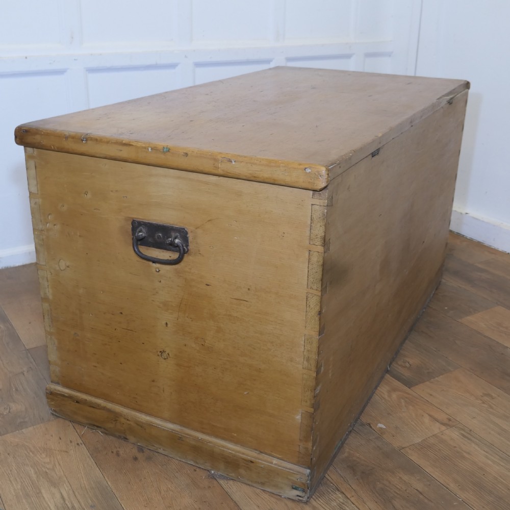 A large rectangular Victorian polished pine blanket box with visible dovetail joints, a flat hinged lid, and a thick wooden plinth base. View VII
