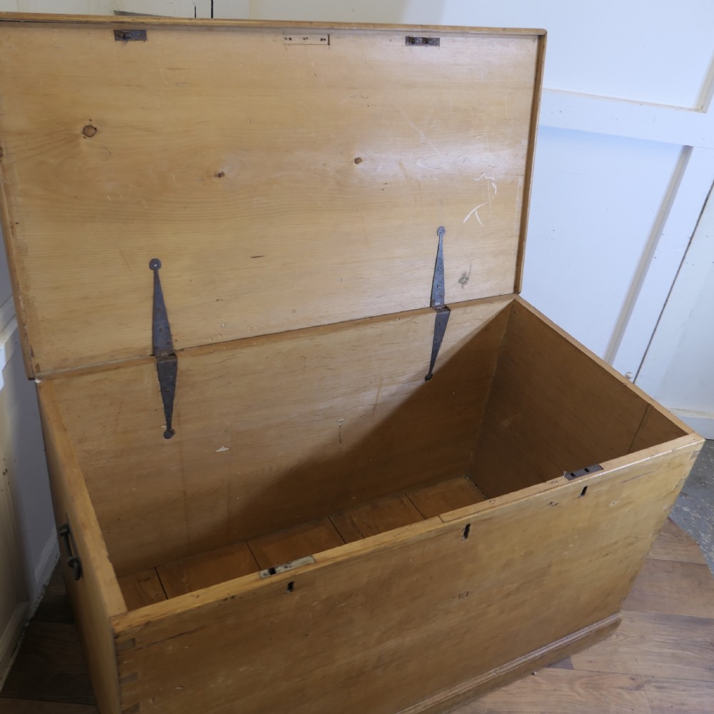 A large rectangular Victorian polished pine blanket box with visible dovetail joints, a flat hinged lid, and a thick wooden plinth base. View VIII