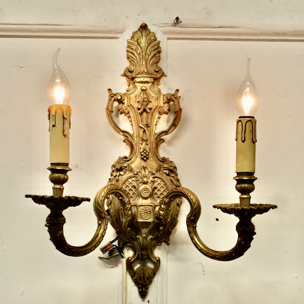 A pair of ornate cast brass twin-arm wall sconces featuring Rococo scrollwork and faux candle drip sleeves. View III