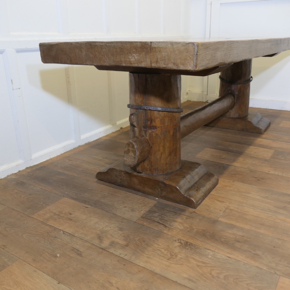 A 19th-century French oak refectory table featuring a thick rectangular top supported by heavy cylindrical pedestal legs connected by a central stretcher.
