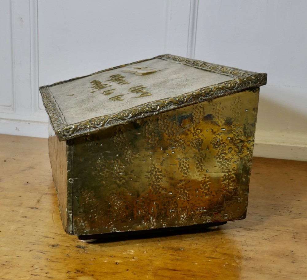 A hand-beaten brass slipper box featuring a sloped lid embossed with footwear imagery and decorative lettering reading Where they ought to be. View II