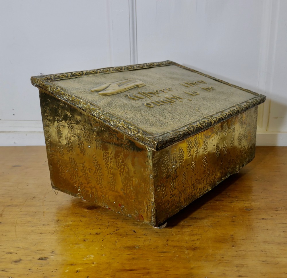 A hand-beaten brass slipper box featuring a sloped lid embossed with footwear imagery and decorative lettering reading Where they ought to be. View III