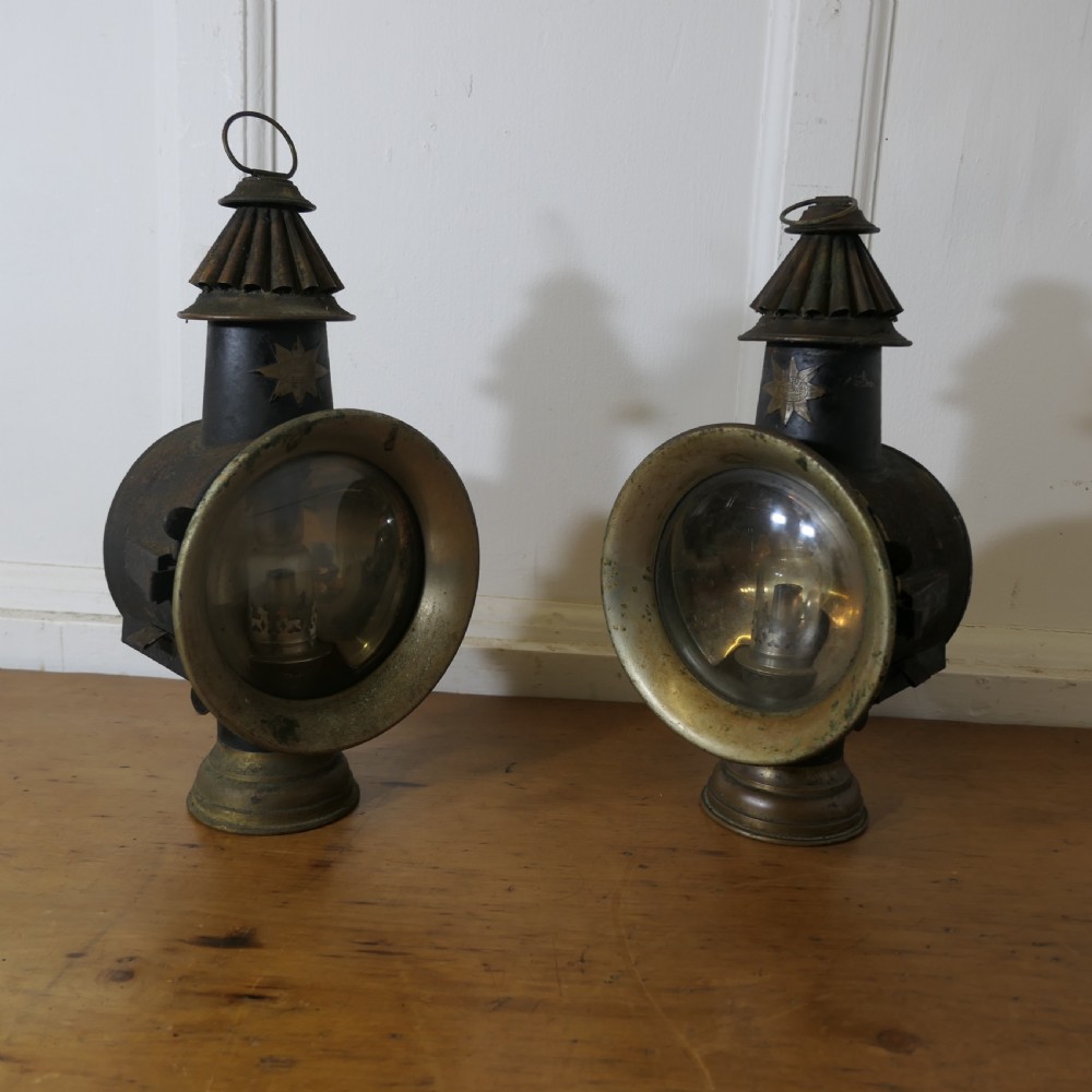 A pair of 19th-century French brass and iron carriage lamps with fluted chimney tops, brass star emblems, and circular convex glass lenses.