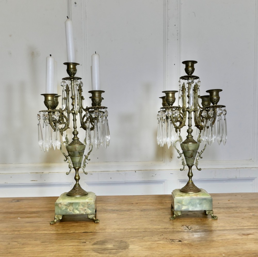 A pair of cast brass five-branch candelabra featuring green onyx stone urns, plinths, and clear crystal glass prisms.