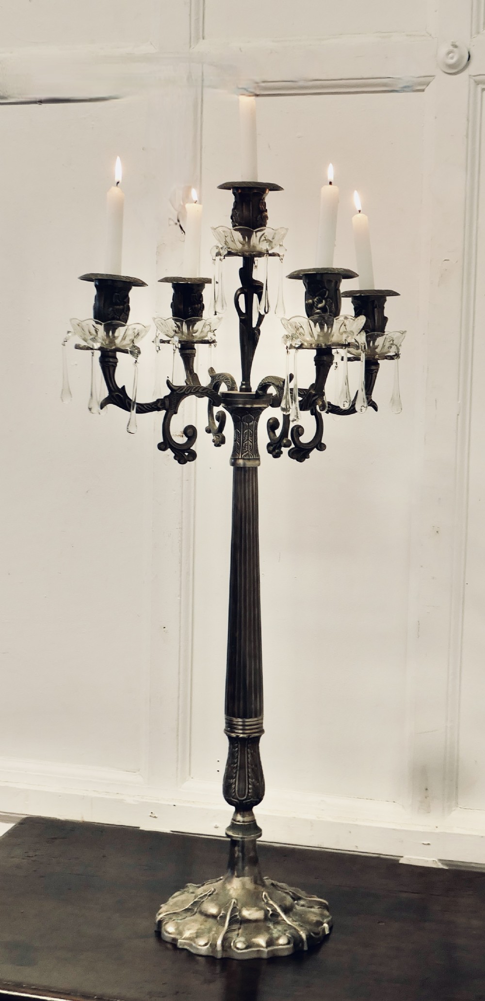 An Art Nouveau silvered metal candelabra featuring five scrolling branches, crystal drip pans with hanging drops, and an ornate fluted central column.