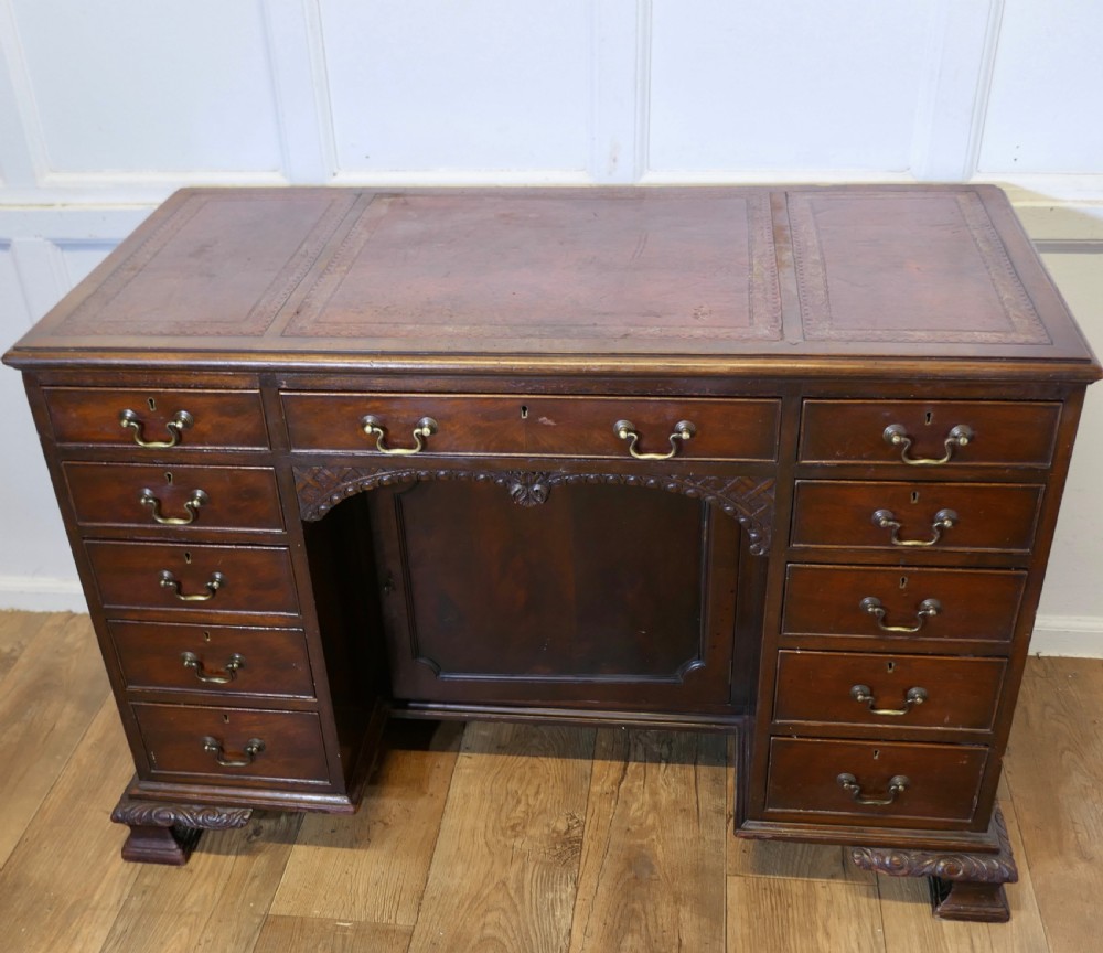 A large dark walnut Victorian kneehole desk featuring ten drawers with brass handles, a central recessed cupboard, and carved feet. View II