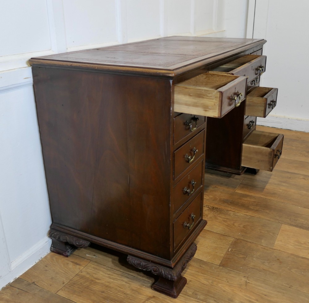 A large dark walnut Victorian kneehole desk featuring ten drawers with brass handles, a central recessed cupboard, and carved feet. View III