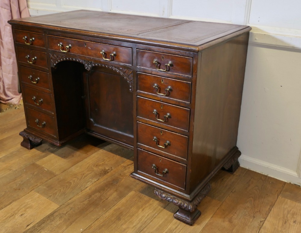 A large dark walnut Victorian kneehole desk featuring ten drawers with brass handles, a central recessed cupboard, and carved feet. View VI