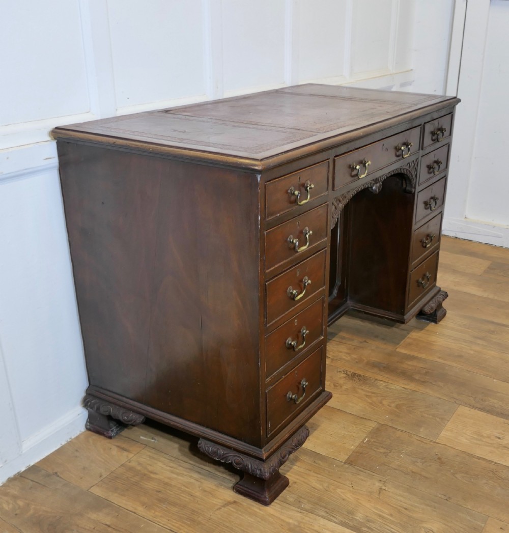A large dark walnut Victorian kneehole desk featuring ten drawers with brass handles, a central recessed cupboard, and carved feet. View VII