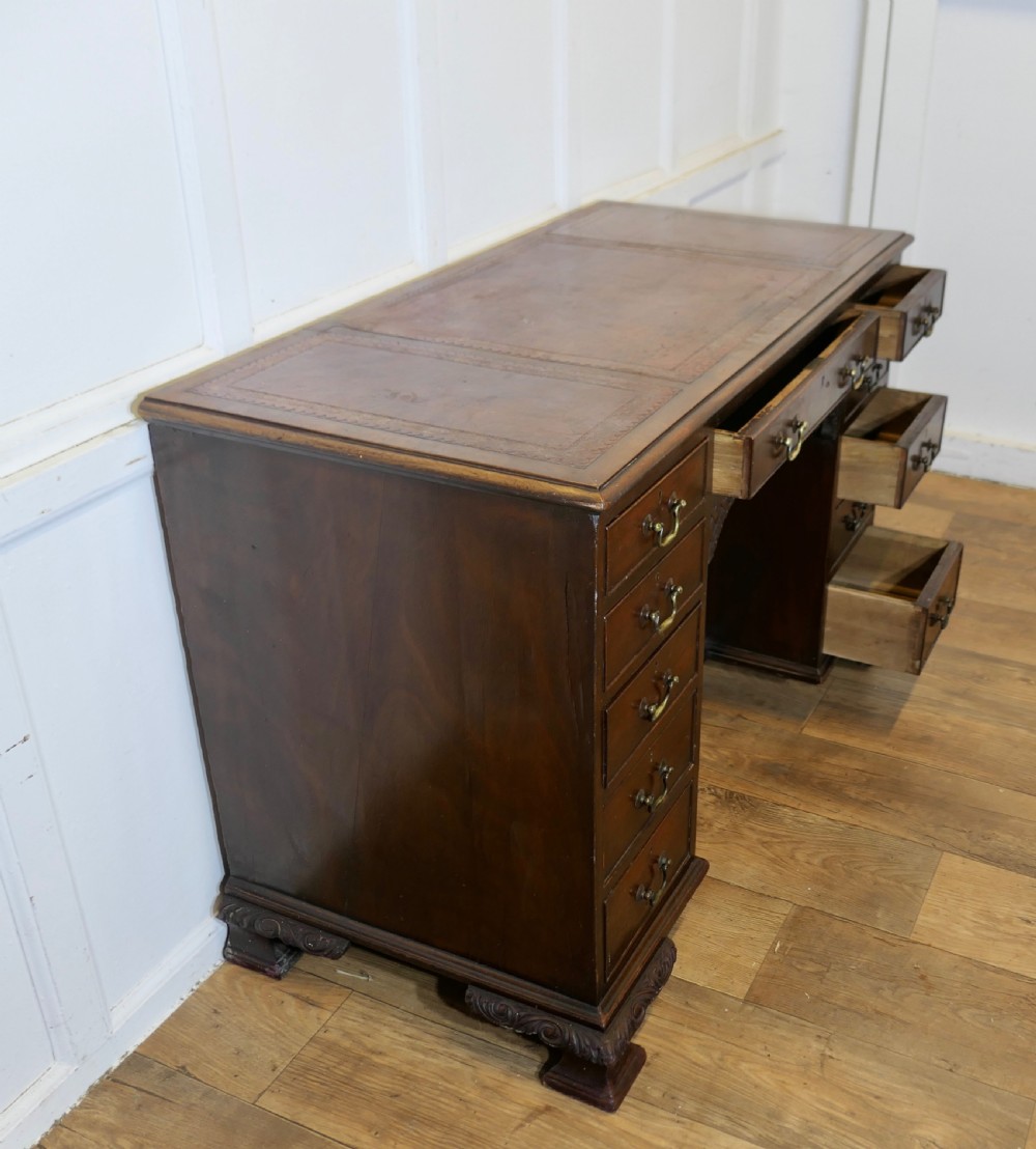 A large dark walnut Victorian kneehole desk featuring ten drawers with brass handles, a central recessed cupboard, and carved feet. View VIII