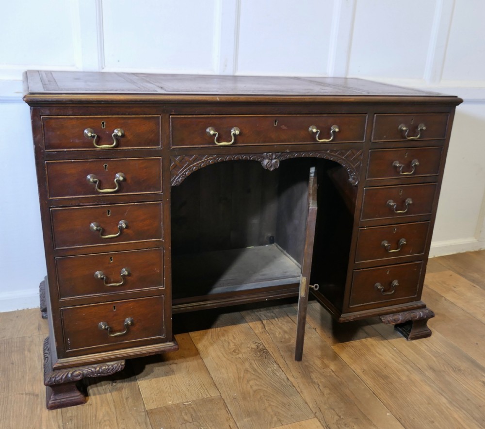 A large dark walnut Victorian kneehole desk featuring ten drawers with brass handles, a central recessed cupboard, and carved feet. View IX