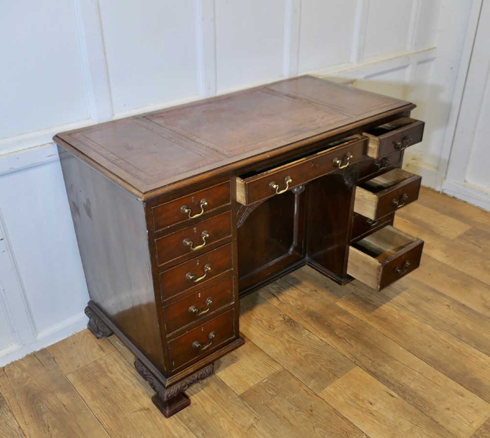 A large dark walnut Victorian kneehole desk featuring ten drawers with brass handles, a central recessed cupboard, and carved feet. View XI