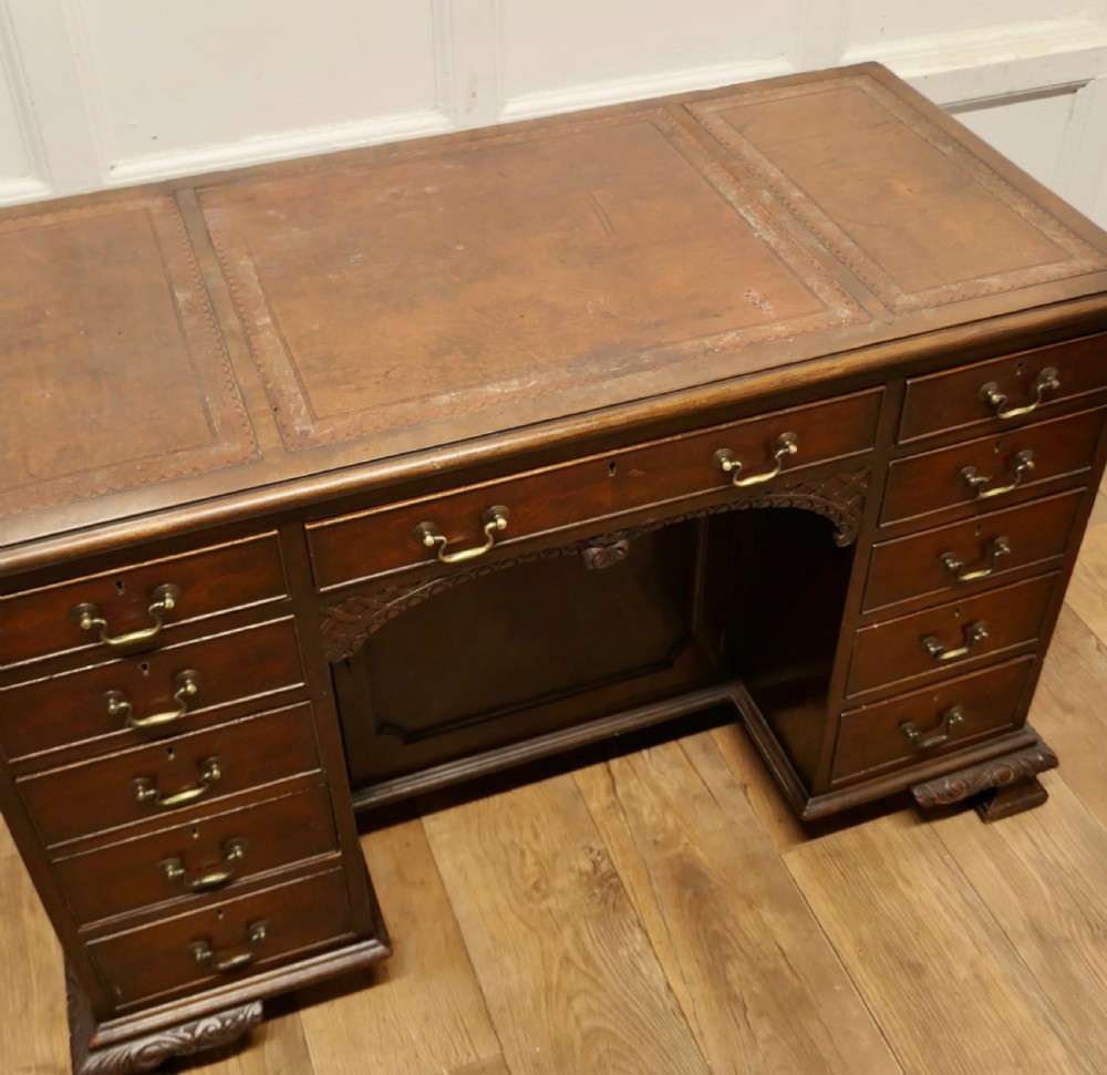 A large dark walnut Victorian kneehole desk featuring ten drawers with brass handles, a central recessed cupboard, and carved feet. View XII