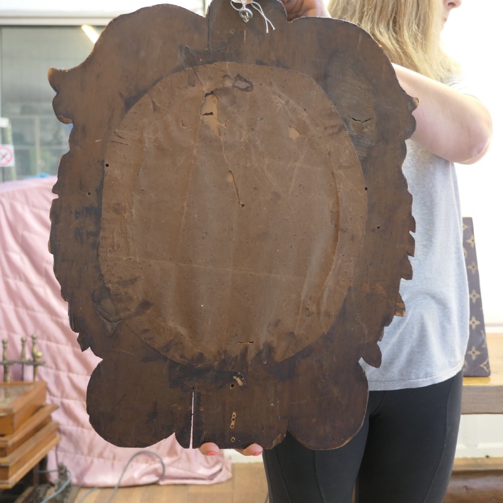 An oval glass mirror enclosed within a deeply carved dark oak frame featuring floral and leaf relief details. View VI