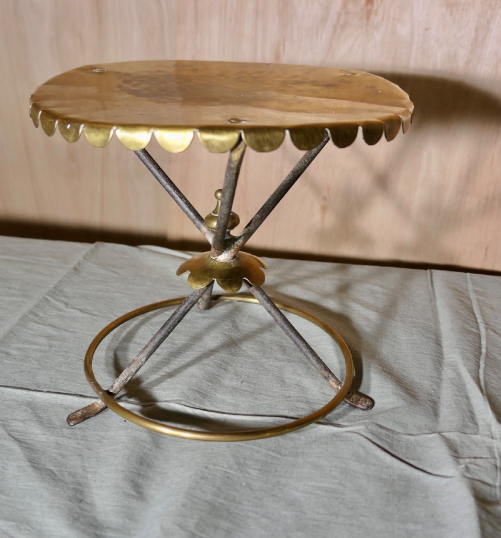 An antique brass and iron gypsy trivet featuring a scalloped brass top plate supported by crossed iron legs and a circular brass base. View II