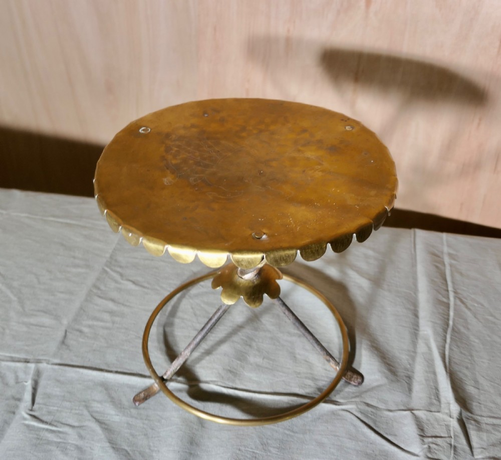 An antique brass and iron gypsy trivet featuring a scalloped brass top plate supported by crossed iron legs and a circular brass base. View IV