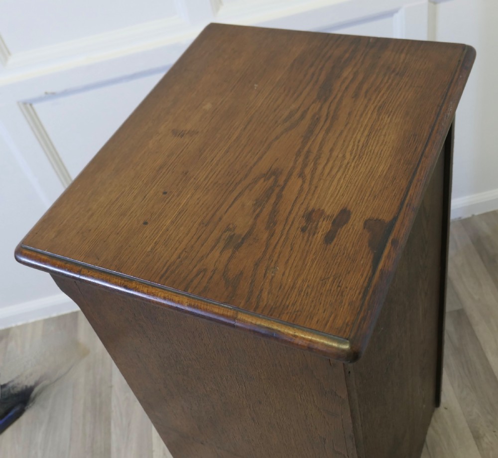 A tall medium brown oak filing cabinet featuring a flexible slatted tambour front, top keyhole escutcheon plate, and a solid plinth base. View VIII