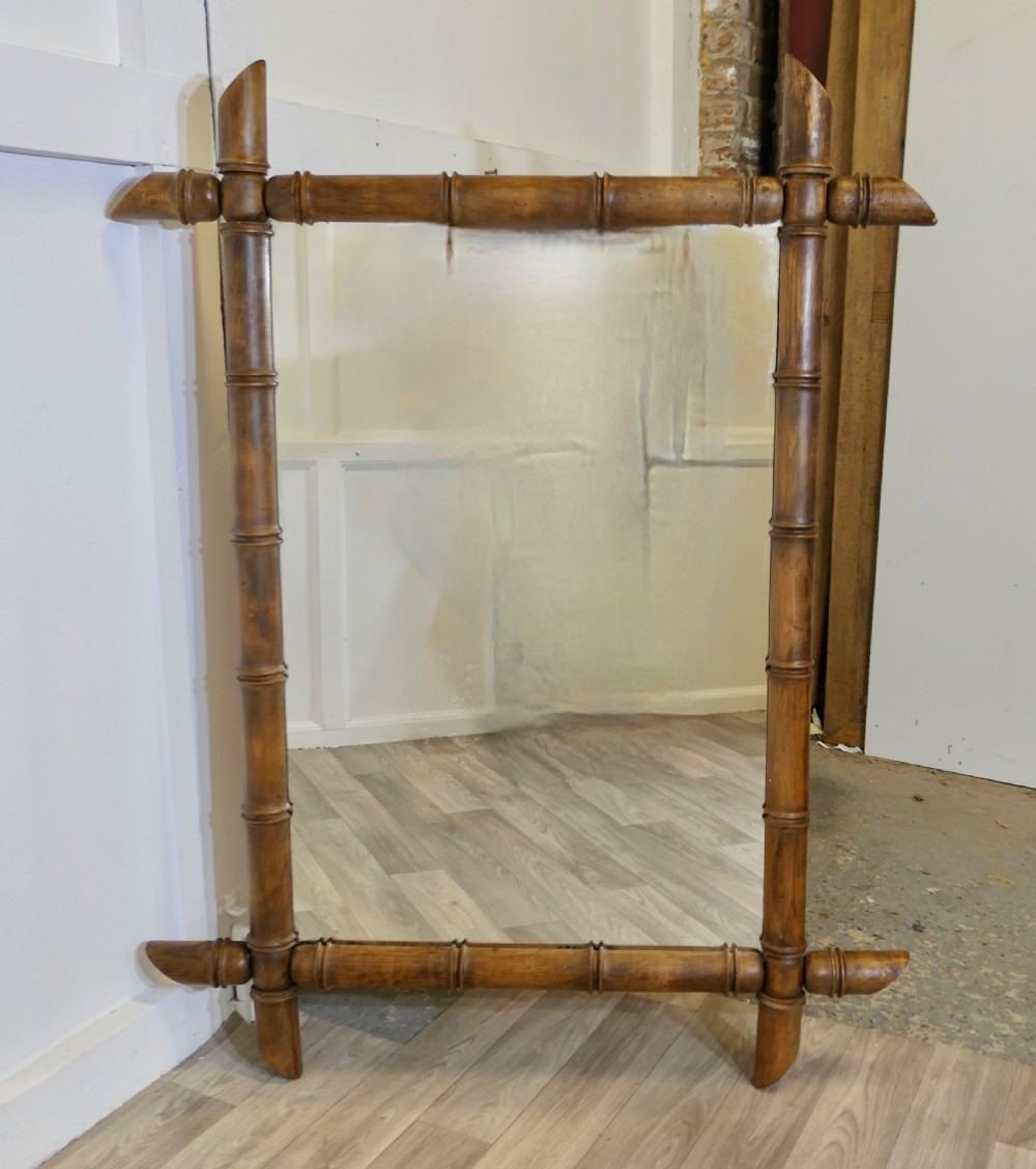 A rectangular wall mirror featuring a carved wooden frame styled to resemble jointed bamboo poles with protruding corner joints. View III
