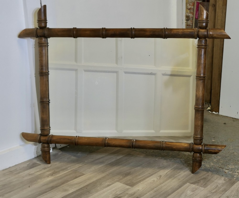 A rectangular wall mirror featuring a carved wooden frame styled to resemble jointed bamboo poles with protruding corner joints. View V