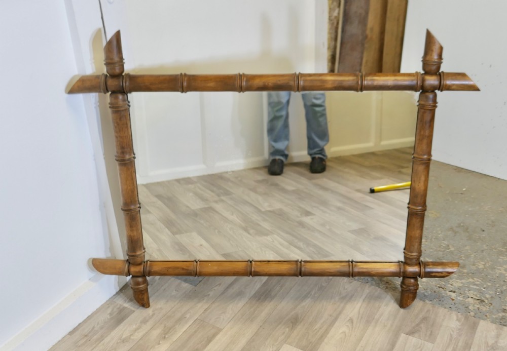 A rectangular wall mirror featuring a carved wooden frame styled to resemble jointed bamboo poles with protruding corner joints. View VIII
