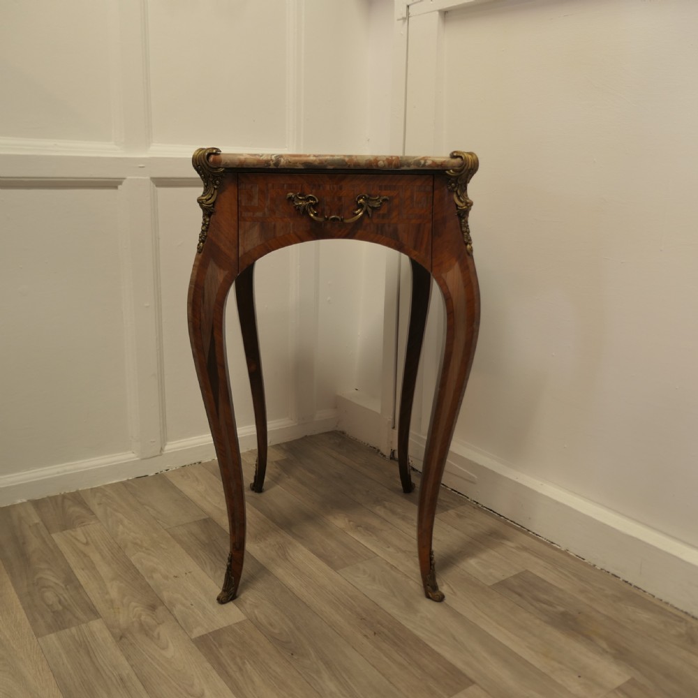 A French Louis XV style side table featuring a marble top, slender cabriole legs, parquetry wood inlay, and decorative ormolu mounts.