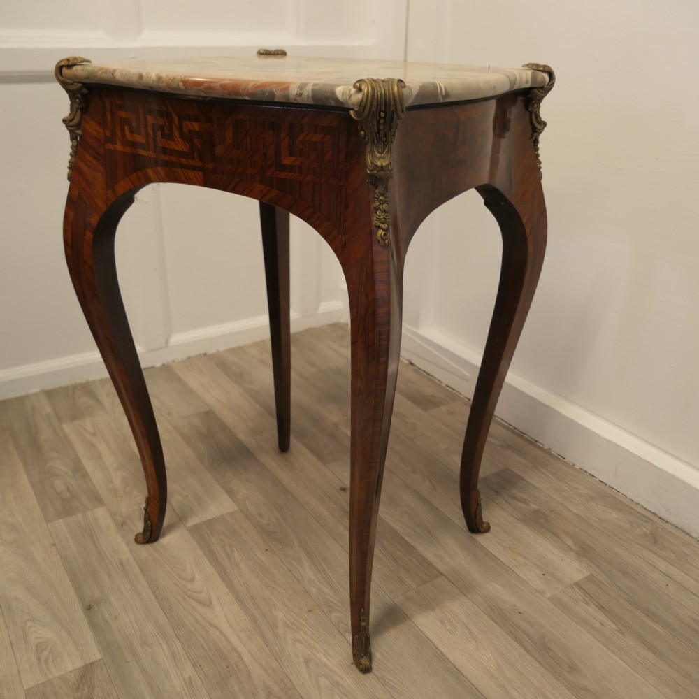 A French Louis XV style side table featuring a marble top, slender cabriole legs, parquetry wood inlay, and decorative ormolu mounts. View VII