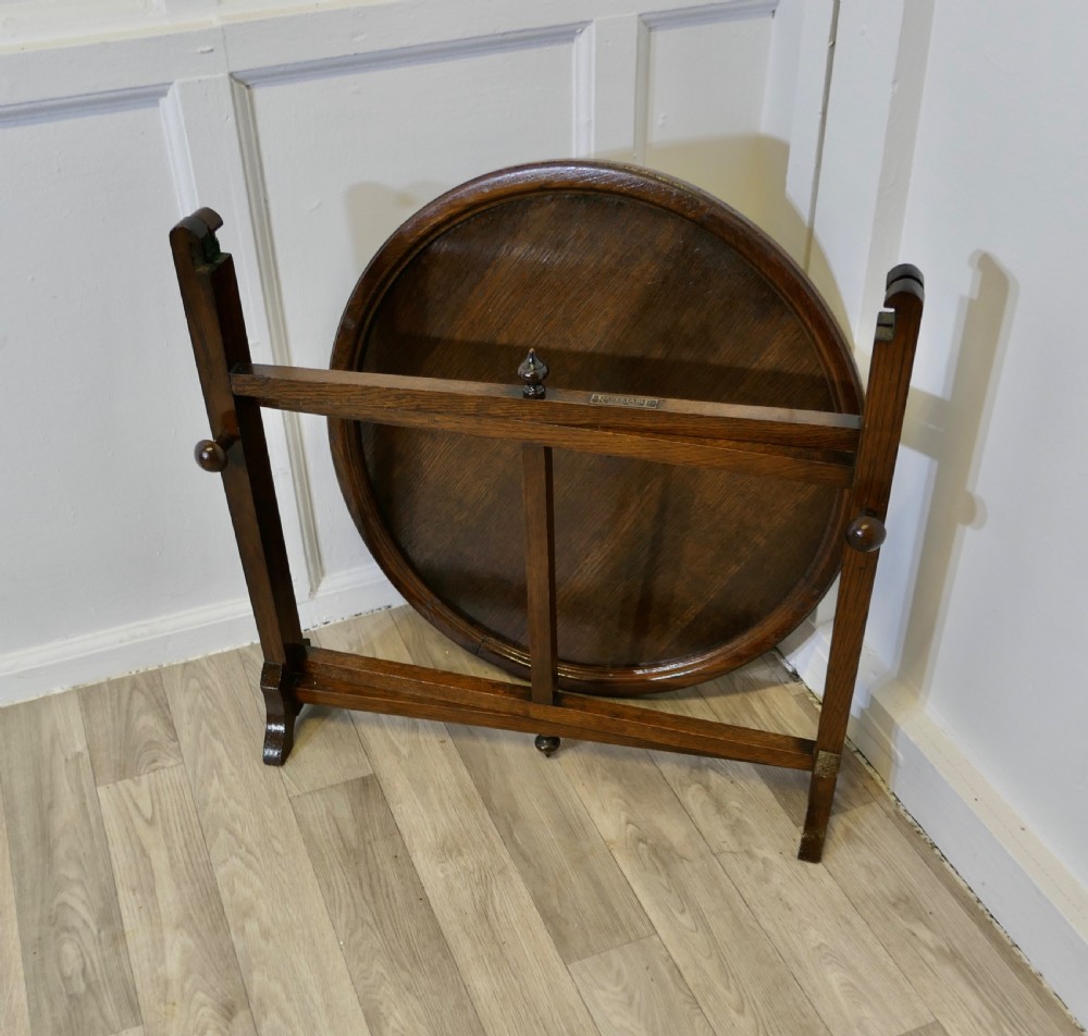 An antique dark oak folding coaching table featuring a circular top mounted on a hinged timber frame. View II