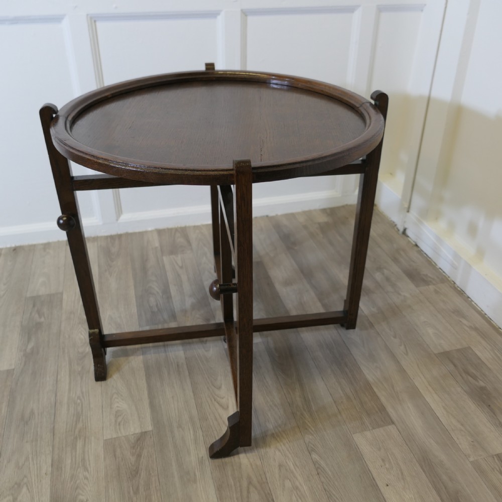 An antique dark oak folding coaching table featuring a circular top mounted on a hinged timber frame. View V