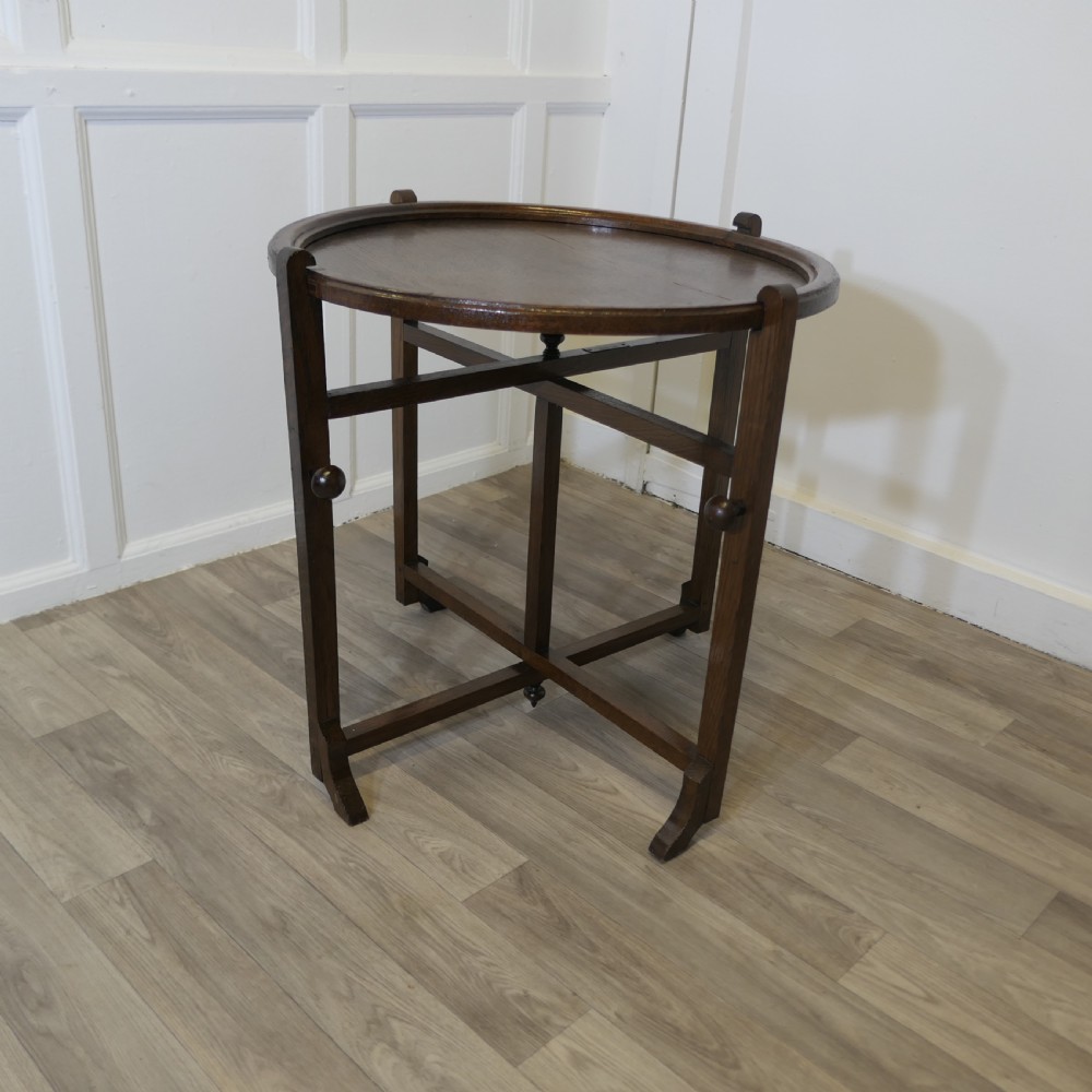 An antique dark oak folding coaching table featuring a circular top mounted on a hinged timber frame. View VI