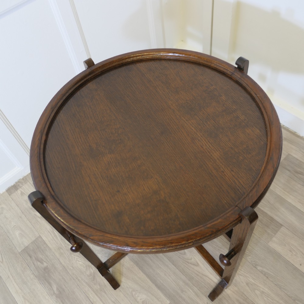 An antique dark oak folding coaching table featuring a circular top mounted on a hinged timber frame. View VII