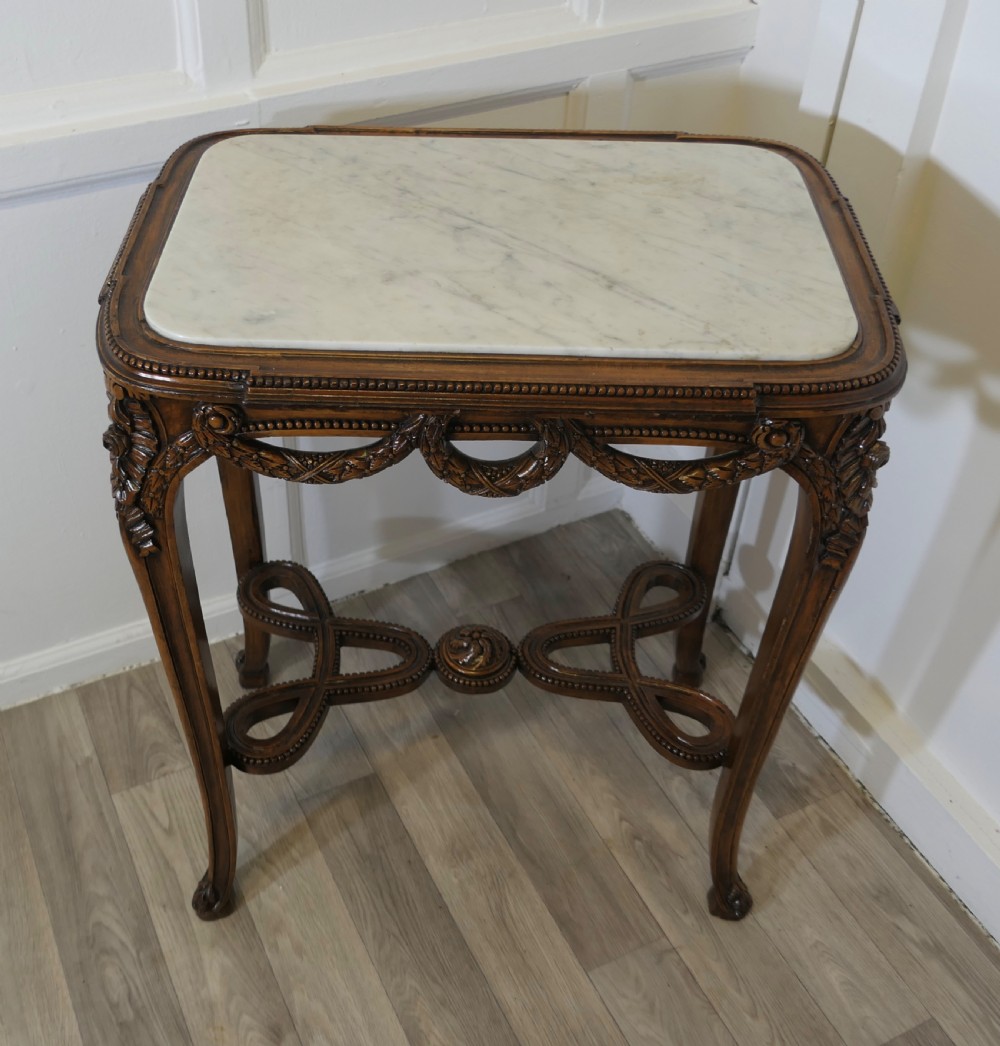 A French carved wooden lamp table featuring a white marble top, sculpted floral garlands, and slender curved legs connected by an ornate stretcher. View II