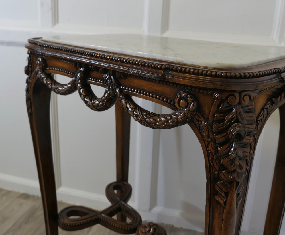 A French carved wooden lamp table featuring a white marble top, sculpted floral garlands, and slender curved legs connected by an ornate stretcher. View III