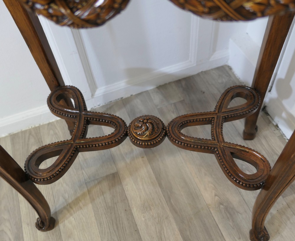 A French carved wooden lamp table featuring a white marble top, sculpted floral garlands, and slender curved legs connected by an ornate stretcher. View V