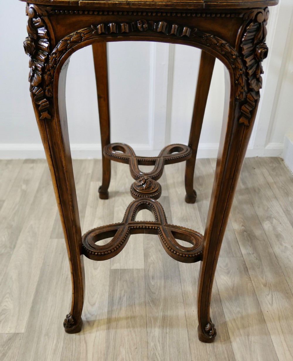 A French carved wooden lamp table featuring a white marble top, sculpted floral garlands, and slender curved legs connected by an ornate stretcher. View VIII