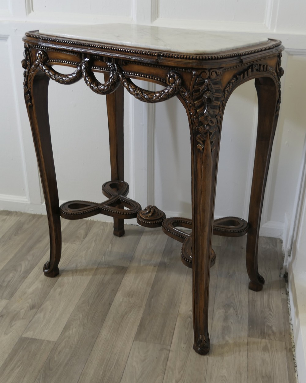 A French carved wooden lamp table featuring a white marble top, sculpted floral garlands, and slender curved legs connected by an ornate stretcher. View X