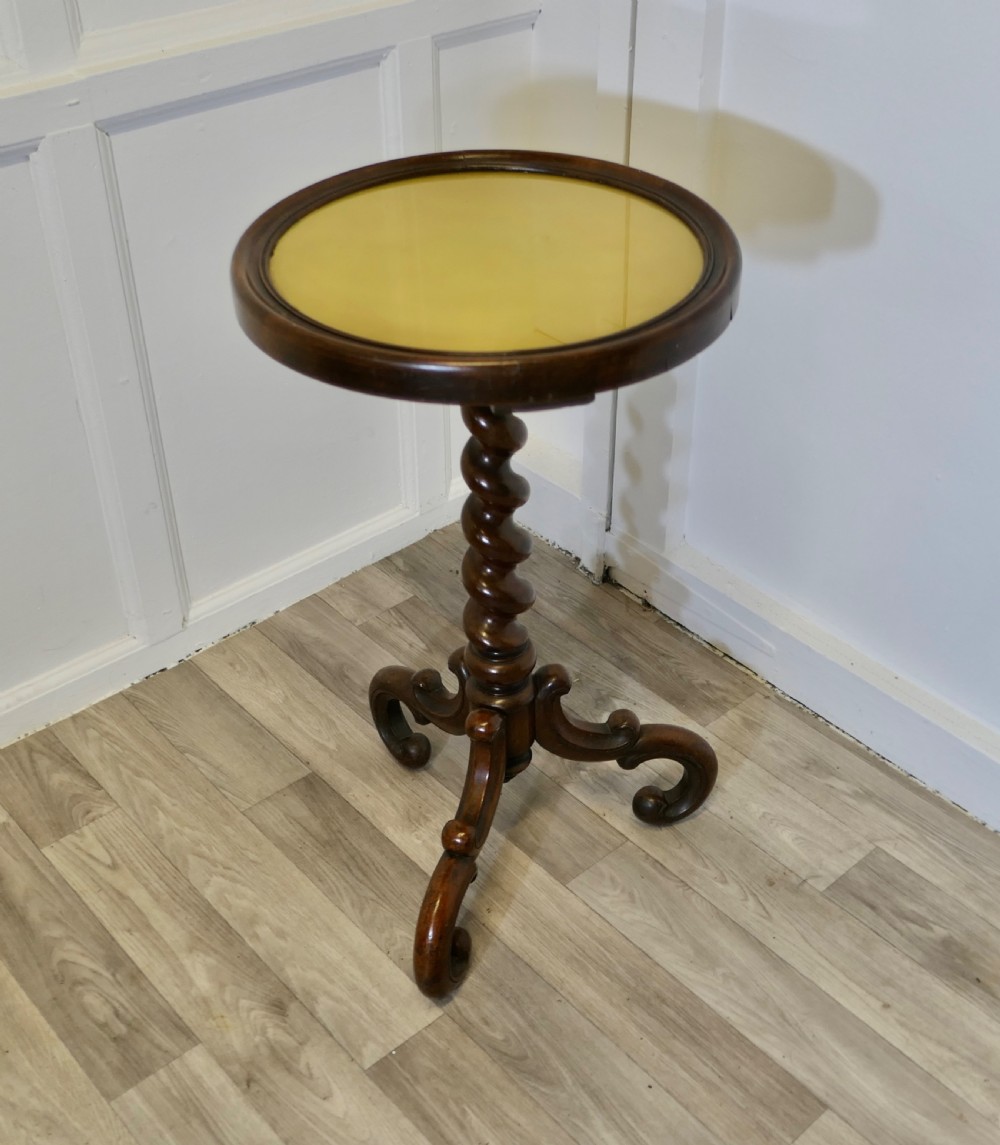 A Victorian dark wood circular wine table featuring a barley twist column and a scrolled tripod base.