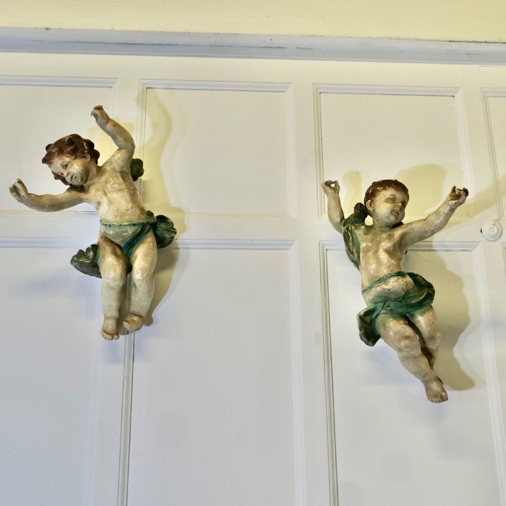 A pair of 19th-century Italian carved wood putti featuring painted dynamic poses and green drapery. View VIII