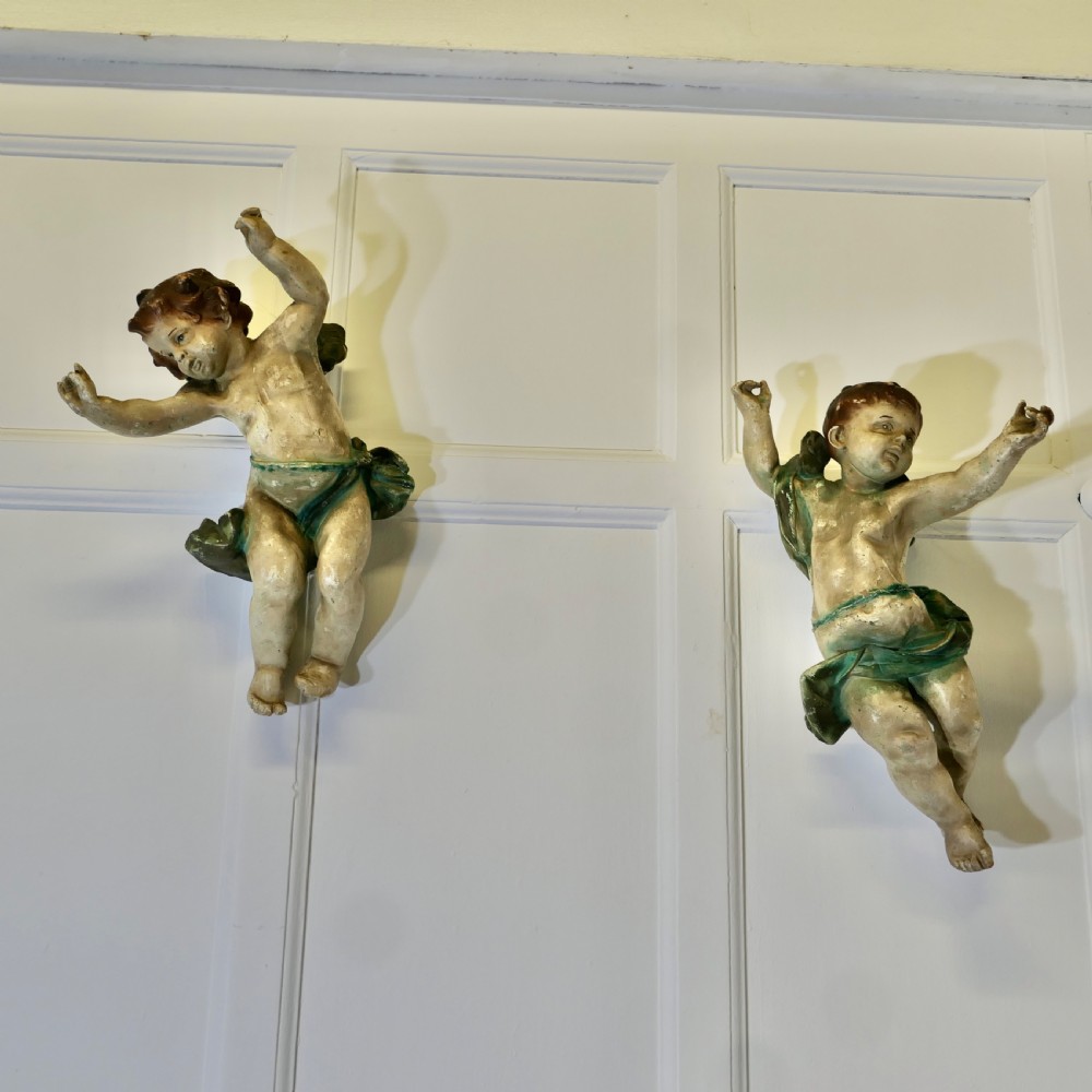 A pair of 19th-century Italian carved wood putti featuring painted dynamic poses and green drapery. View IX