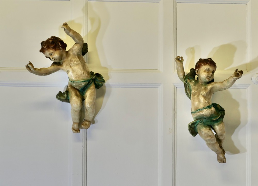 A pair of 19th-century Italian carved wood putti featuring painted dynamic poses and green drapery. View X