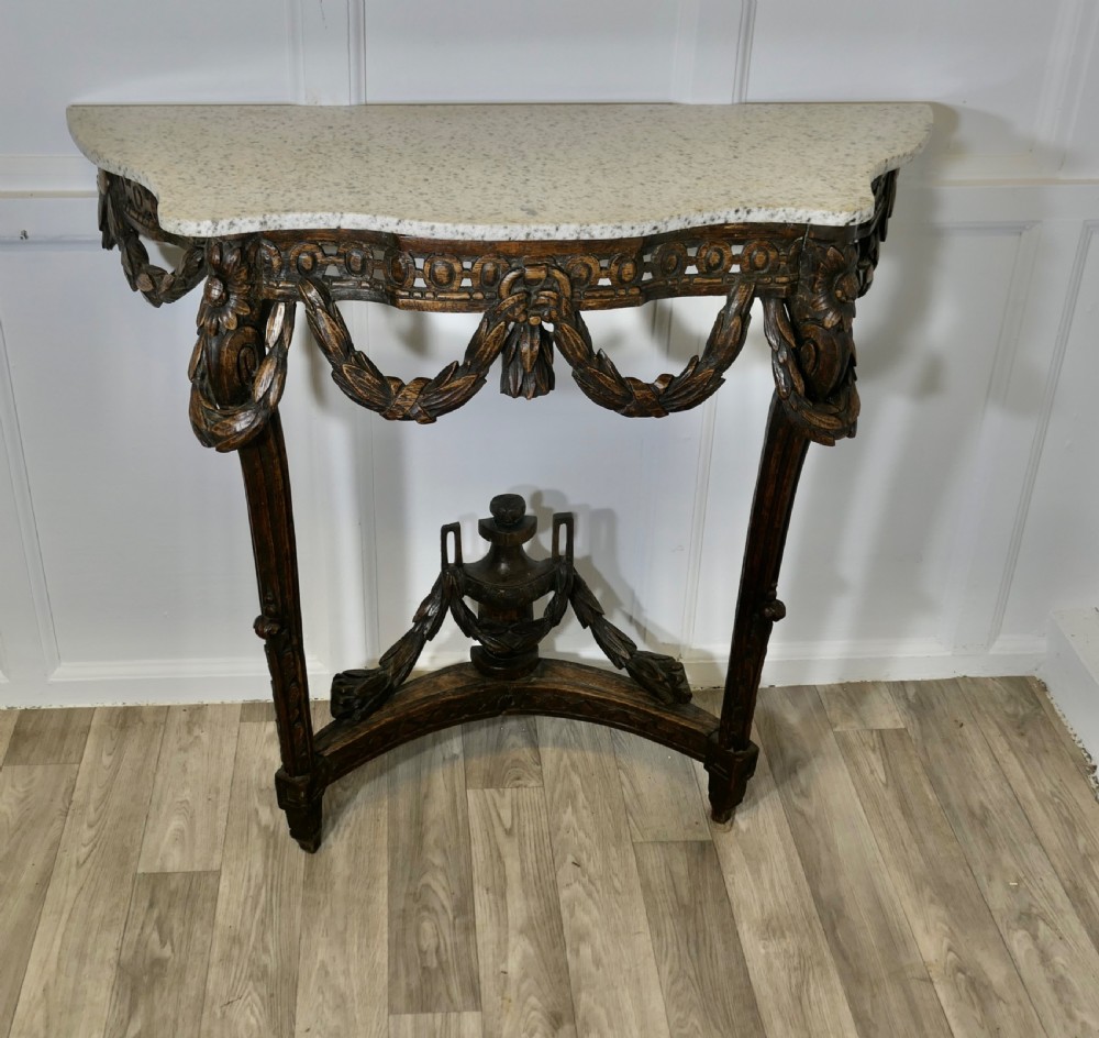 A dark hand-carved wooden French Neoclassical console table featuring drape festoons, a guilloche apron, a curved stretcher with an urn finial, and a light granite top. View III