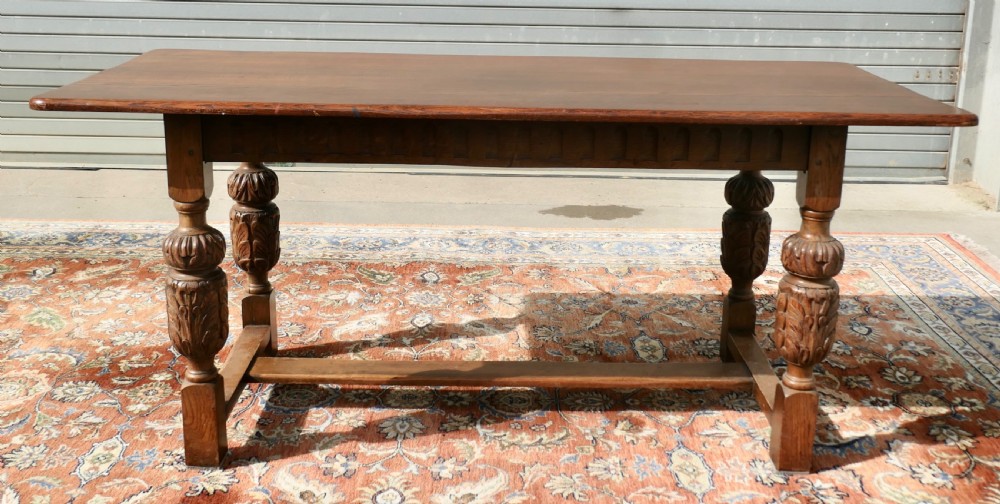 A rectangular solid oak refectory dining table featuring carved bulbous turned legs joined by a low central stretcher. View V