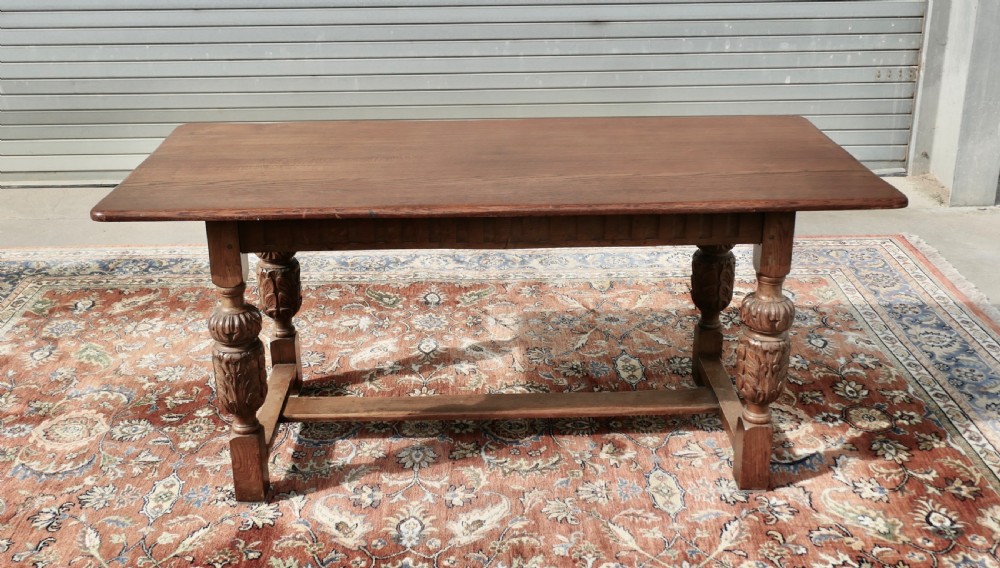A rectangular solid oak refectory dining table featuring carved bulbous turned legs joined by a low central stretcher. View VI