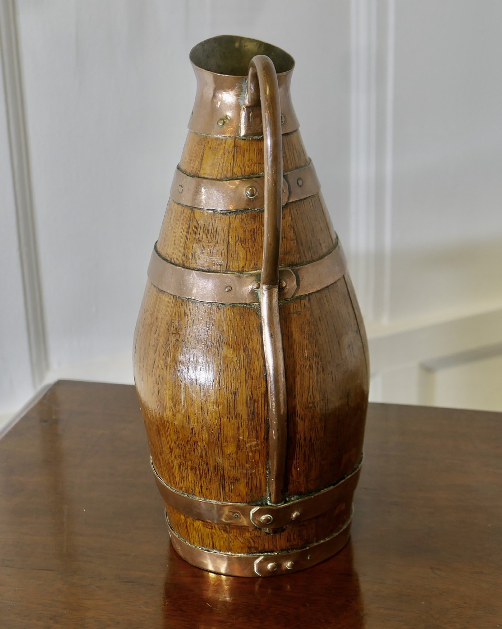 A French Arts and Crafts staved golden oak cider jug featuring copper bands, a copper spout, and a curved copper handle. View II