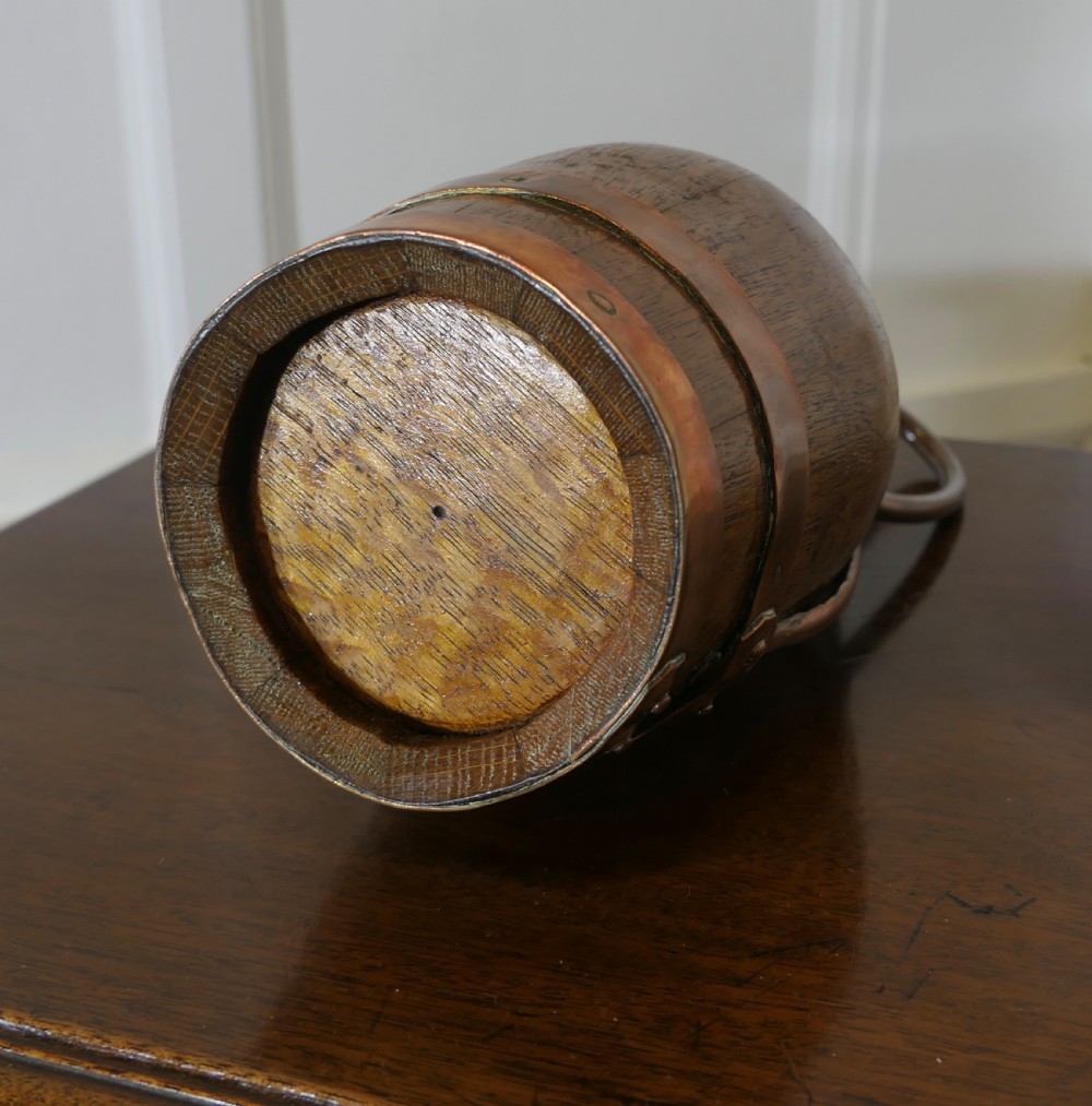 A French Arts and Crafts staved golden oak cider jug featuring copper bands, a copper spout, and a curved copper handle. View VII